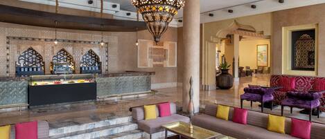 A lobby with a reception desk, sofas, a chandelier, and a patterned floor.