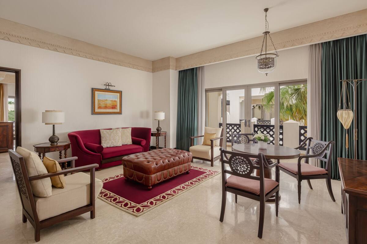 Uma sala de estar ampla com um sofá vermelho, uma mesa de centro de madeira e um espaço de jantar com mesa redonda e cadeiras.