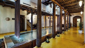Un intérieur spacieux avec de hautes poutres en bois, une fontaine centrale et un plancher poli.