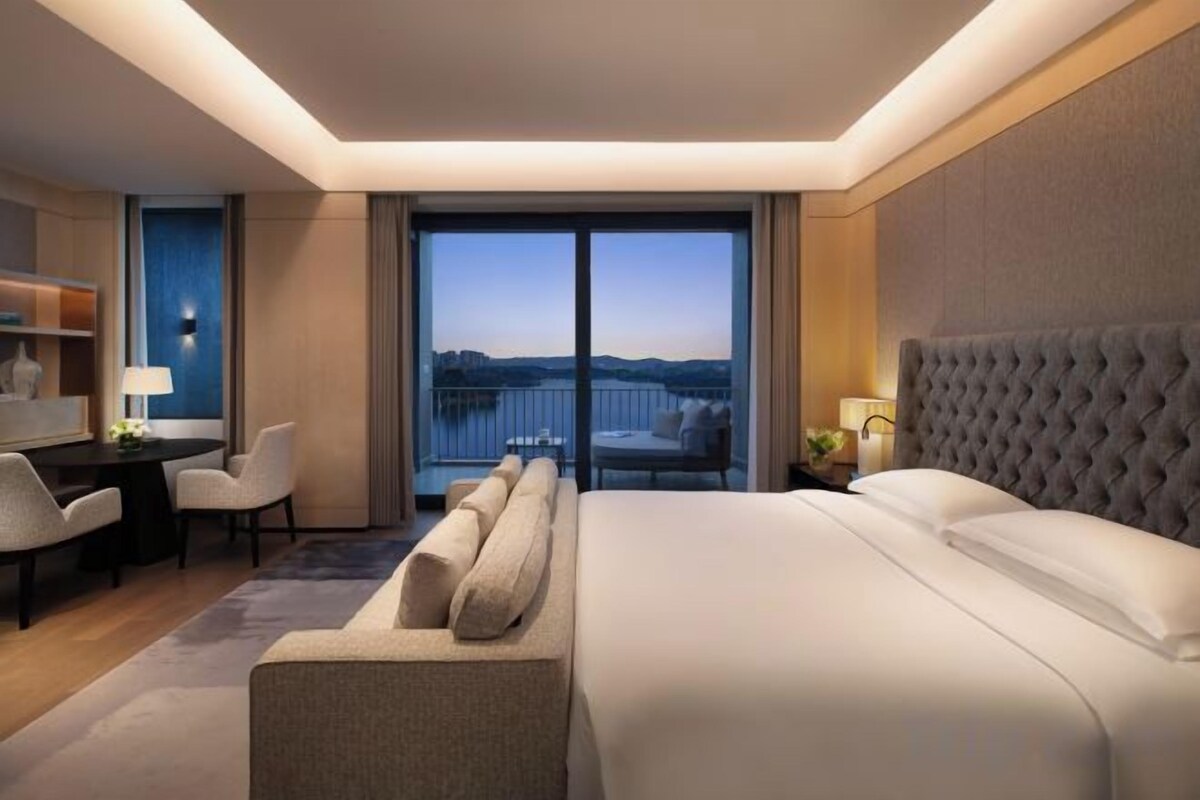 Una habitación de hotel con una cama grande, un escritorio, una silla y un balcón con vistas.