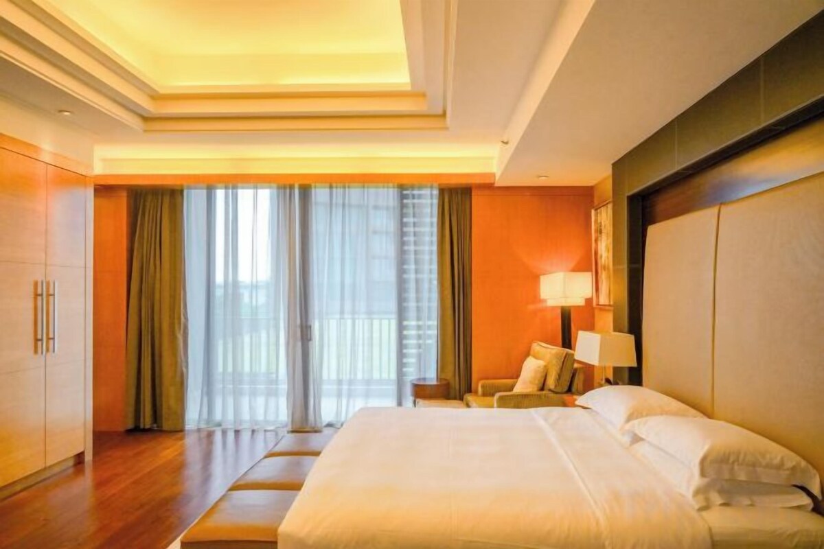 Habitación de hotel con una cama grande, un escritorio y vistas al exterior a través de una puerta corredera.