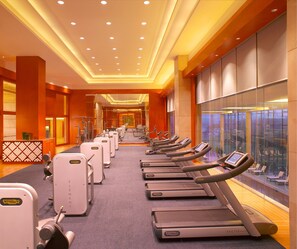 A gym with multiple treadmills and weight machines, a reception desk, and a large window with a view. - Hyatt Regency Dongguan (Dongguan)