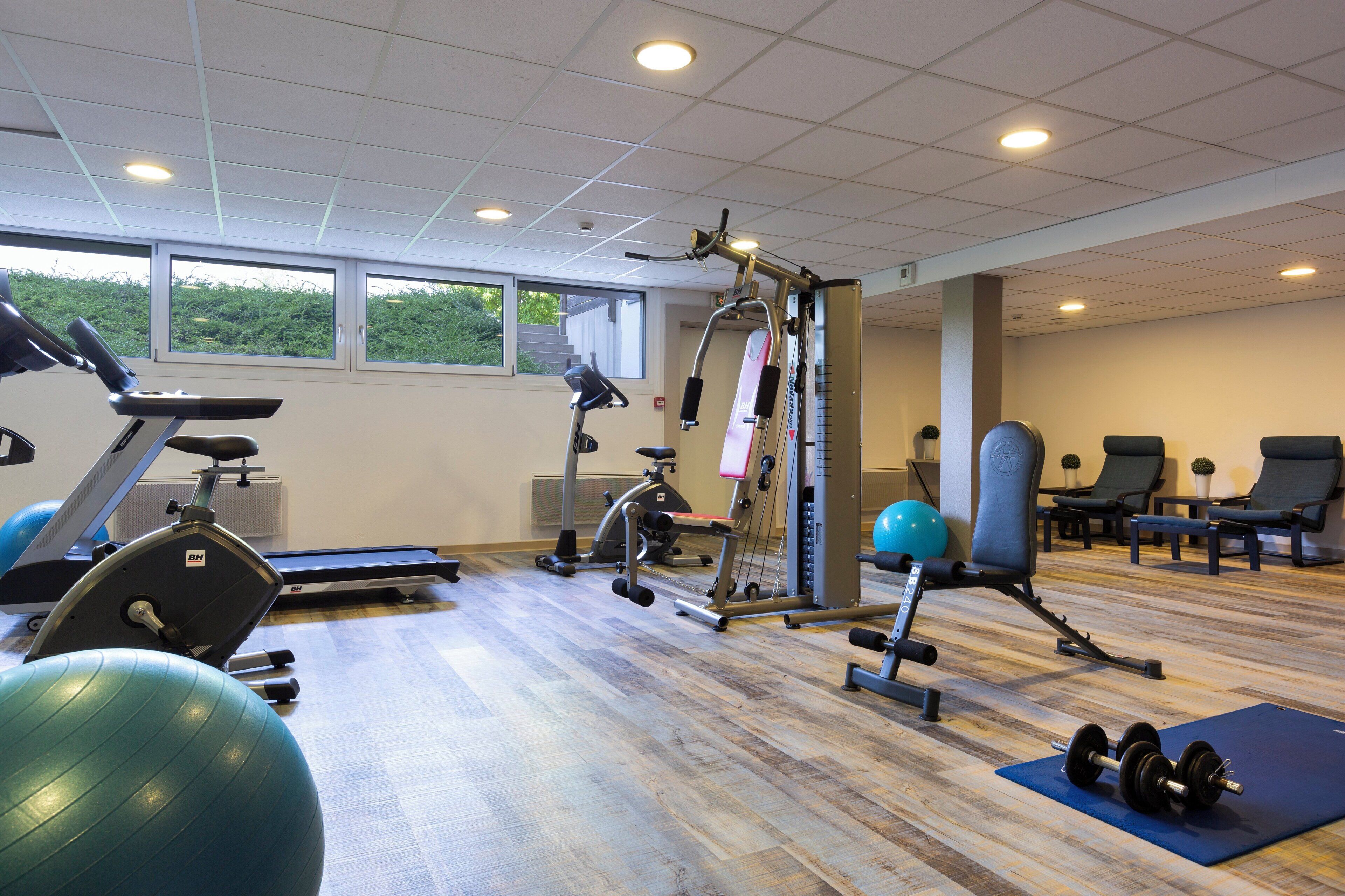Ett gym med träningsutrustning, ett löpband och en roddmaskin.
