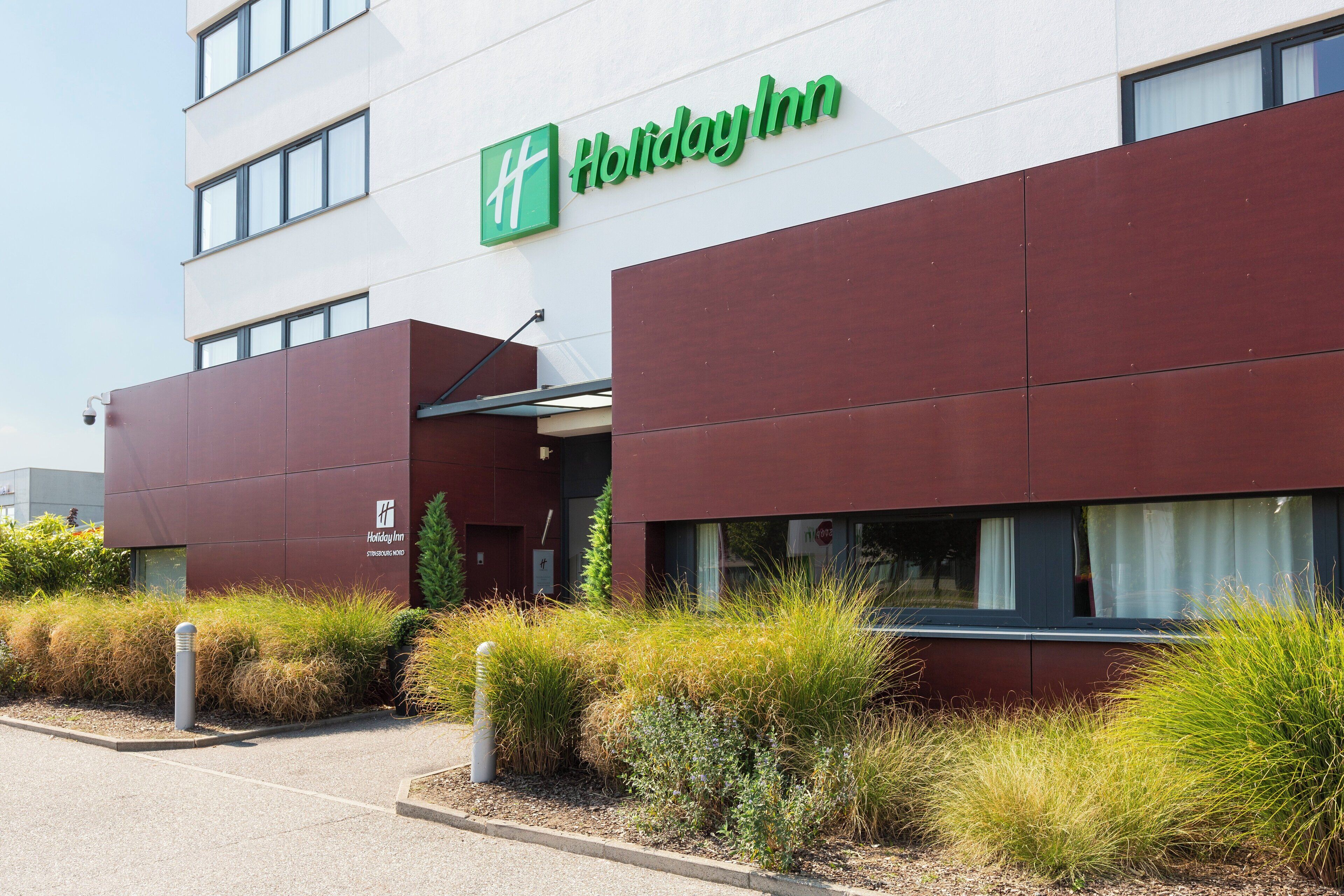 A Holiday Inn building with a modern facade, large windows, and a visible entrance.