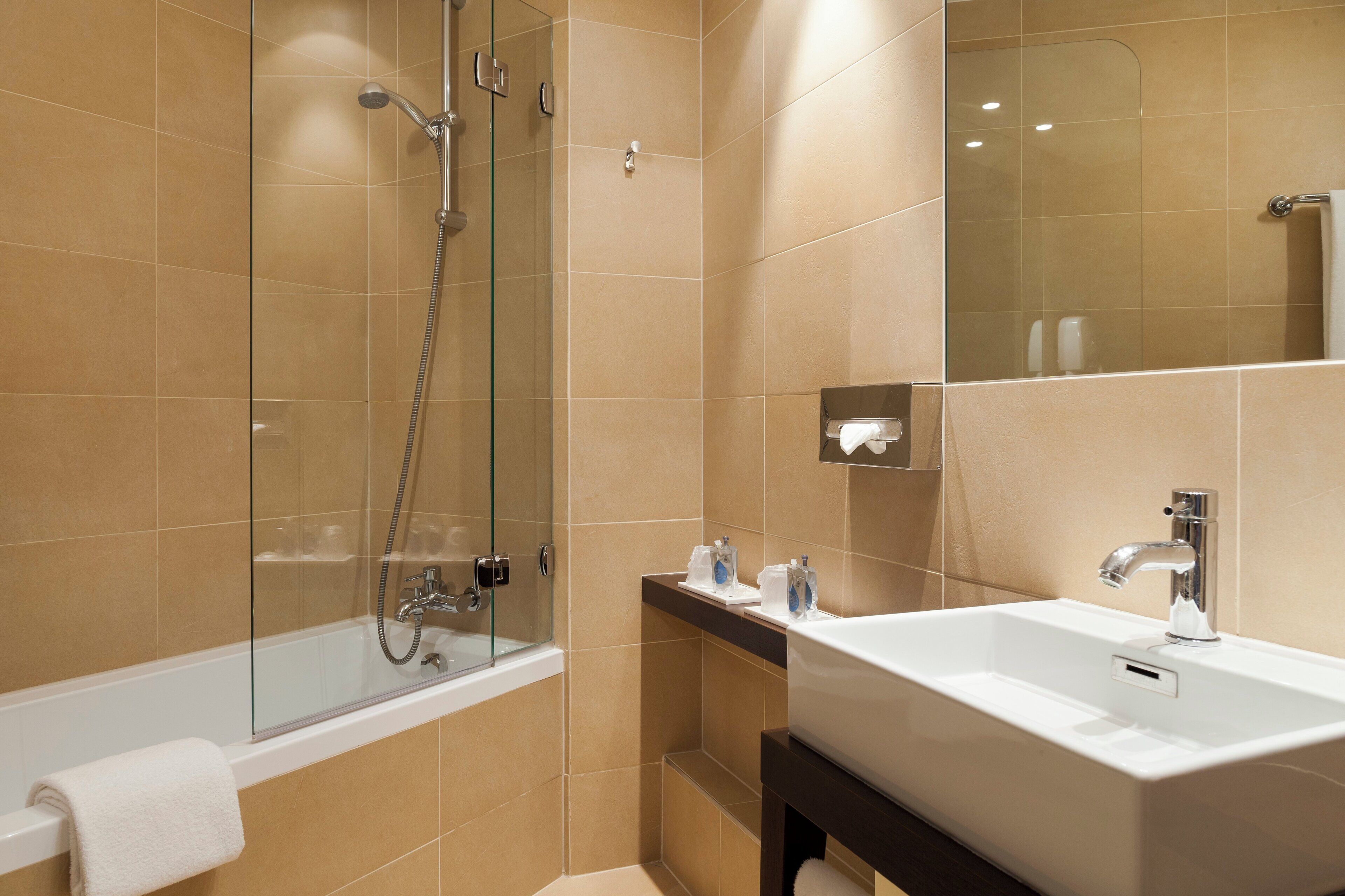 A modern bathroom with a glass-enclosed shower, a white sink, and a mirror.