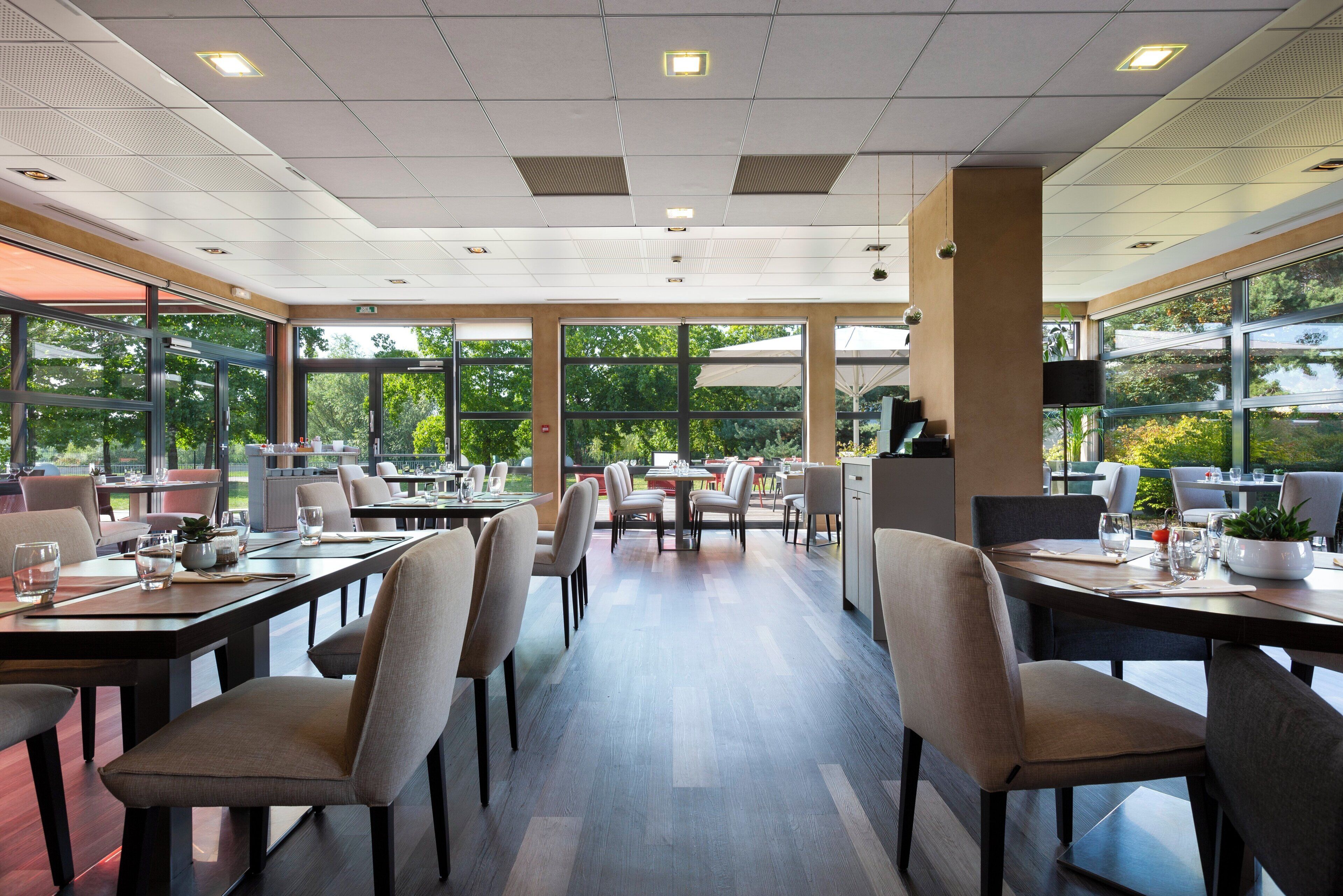 Ein modernes Restaurant mit großen Fenstern, Holztischen und -stühlen.