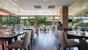 Ein modernes Restaurant mit großen Fenstern, Holztischen und -stühlen.