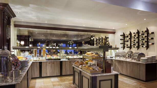 Uma área de buffet com diversos tipos de comida e um suporte para vinhos.