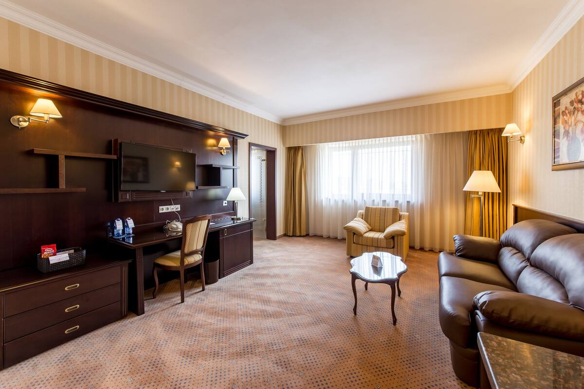 Een hotelkamer met een televisie, bureau, twee stoelen, een bank en een salontafel.