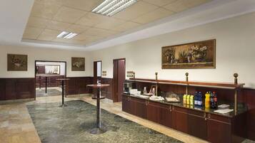 A lobby with a reception desk, a coffee station, and artwork on the walls.