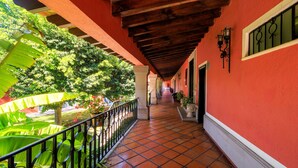 A corridor with red walls, a tiled floor, and a balcony with a railing. - Real de Minas San Miguel de Allende (San Miguel de Allende)