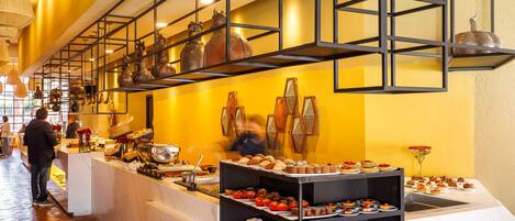 A buffet area with various food items and a decorative wall with hanging objects.
