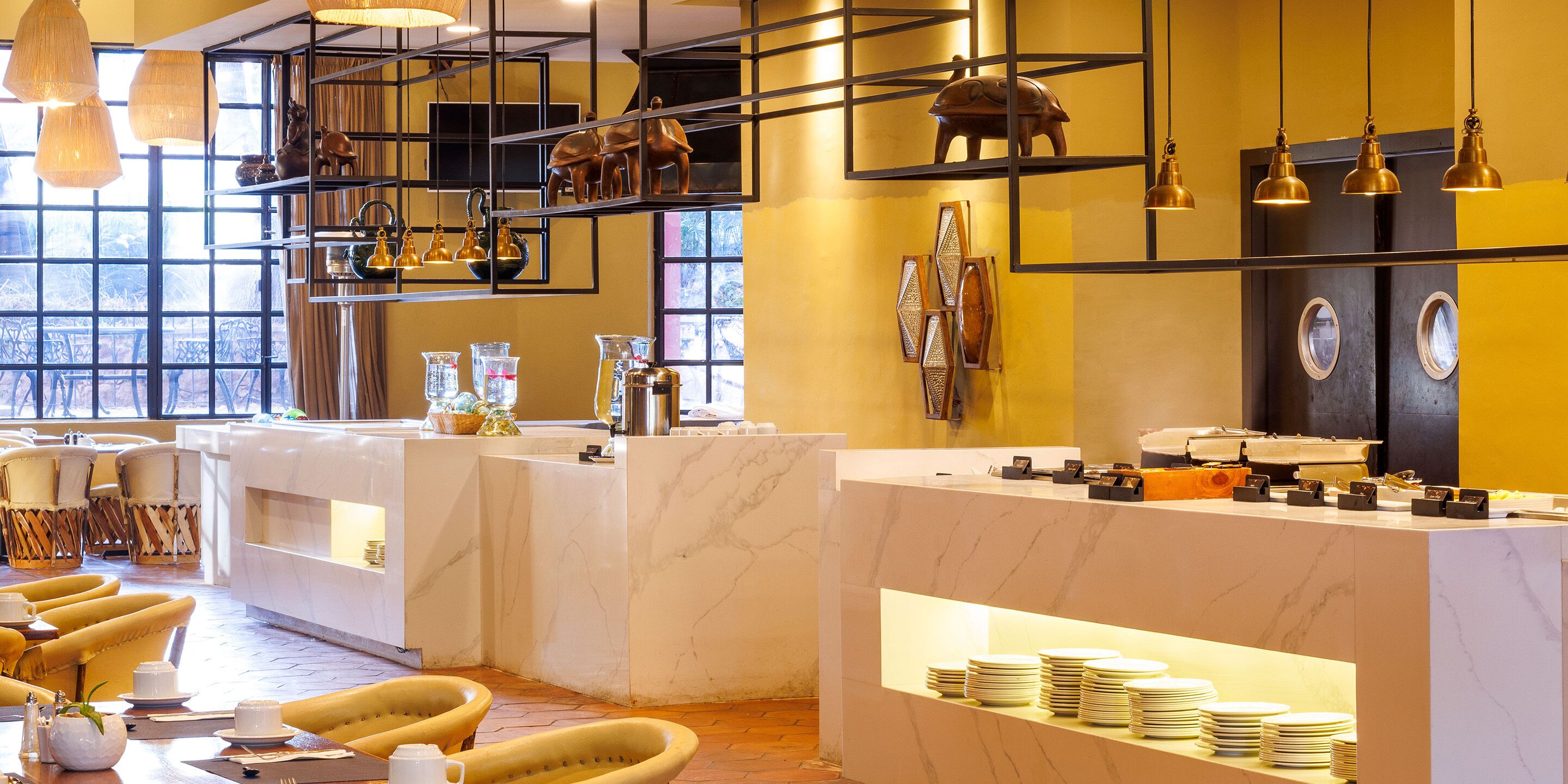 Um hall de hotel com balcões de mármore, paredes amarelas e uma área de estar com cadeiras amarelas.
