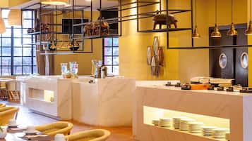 A hotel lobby with marble counters, yellow walls, and a seating area with yellow chairs.