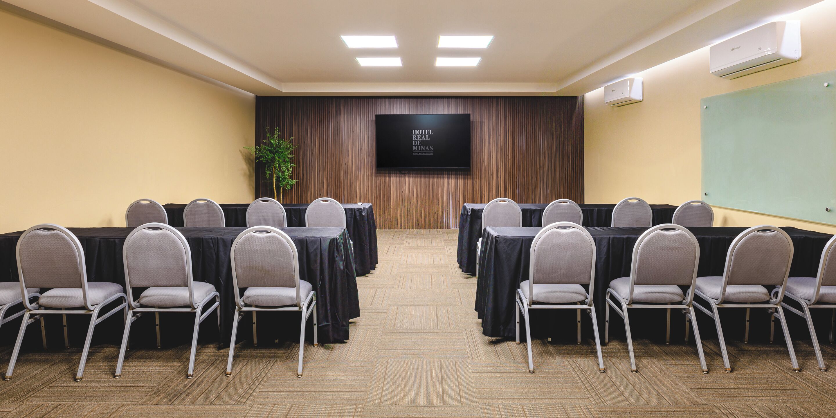 Una sala de conferencias con mesas, sillas, una pantalla de televisión y un equipo de aire acondicionado.