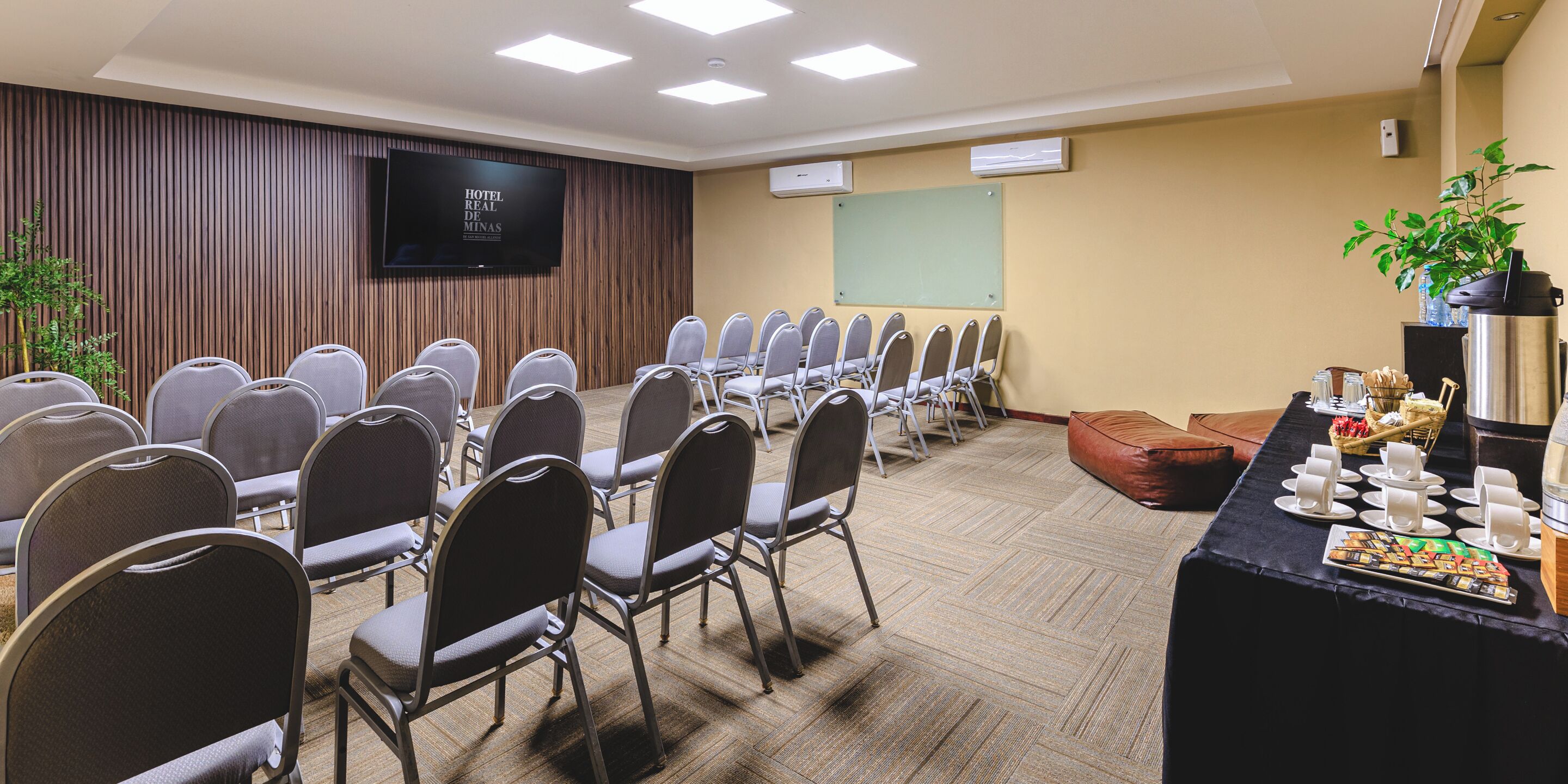 A conference room with rows of chairs, a large screen, a whiteboard, and a buffet table with food and drinks.