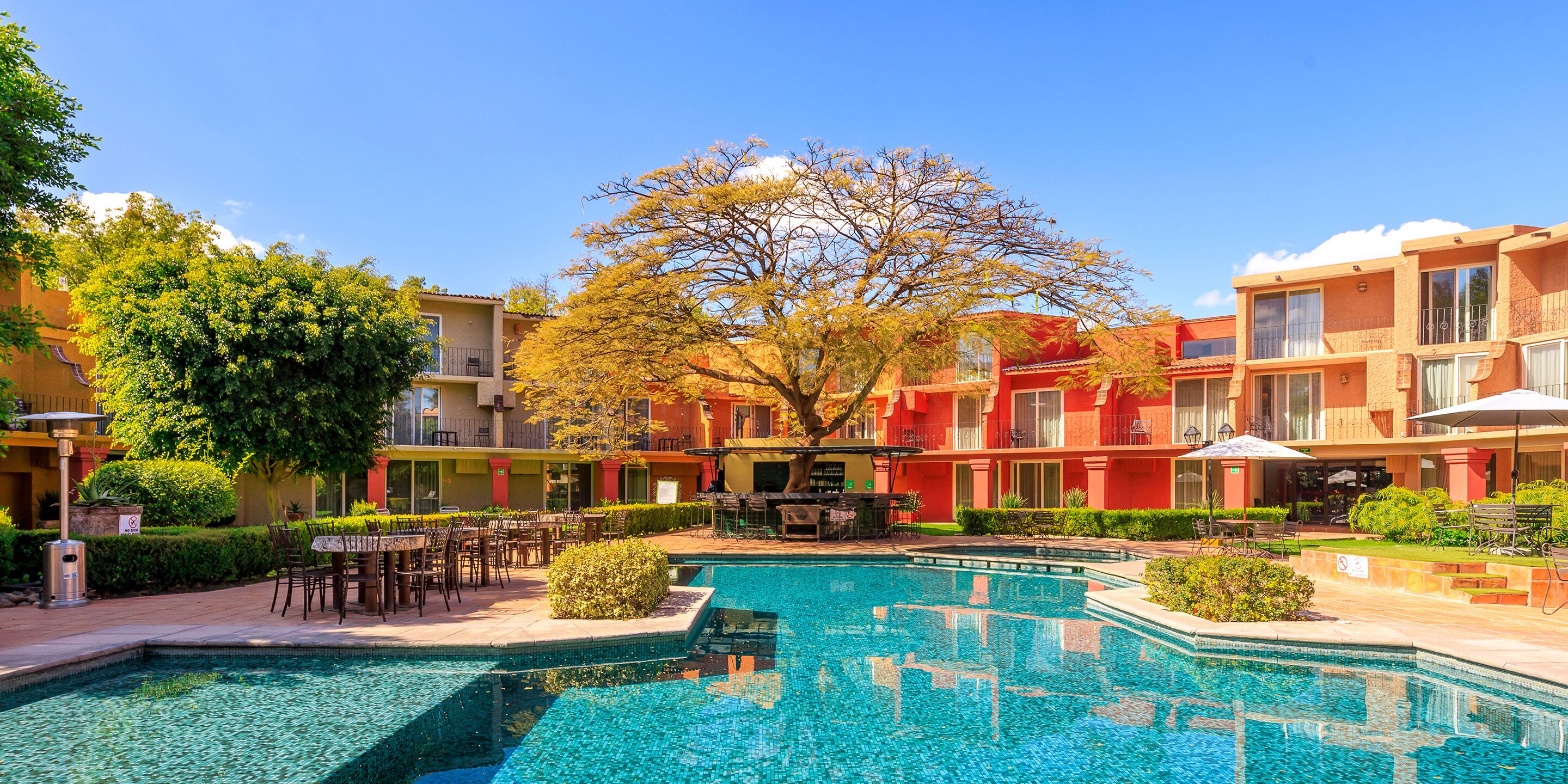 Una piscina al aire libre, sombrillas, sillones reclinables de piscina