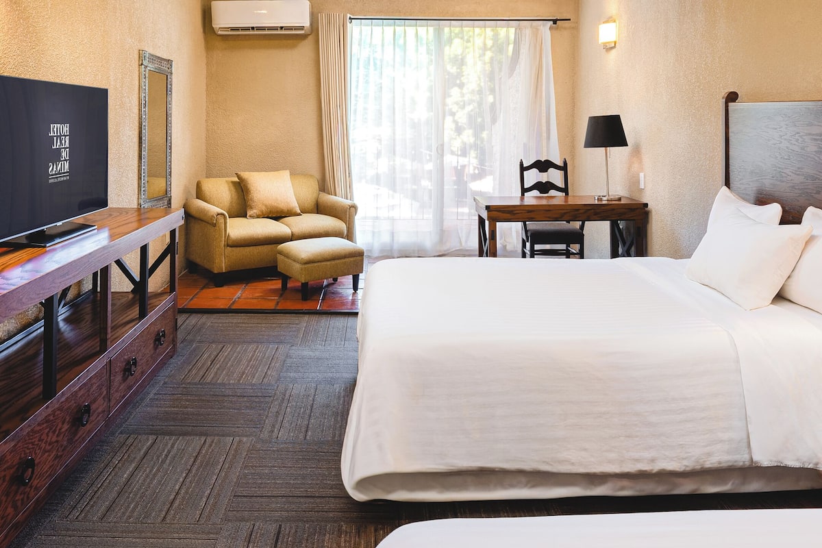 Une chambre d’hôtel équipée d ’un lit, d’un bureau, d’une chaise, d’une télévision et d’un téléphone sur la table de chevet.