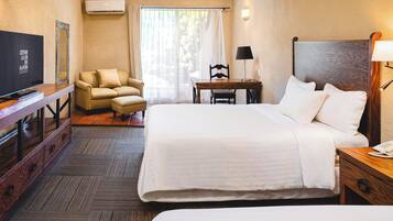 A hotel room with a bed, a desk, a chair, a TV, and a phone on the bedside table.