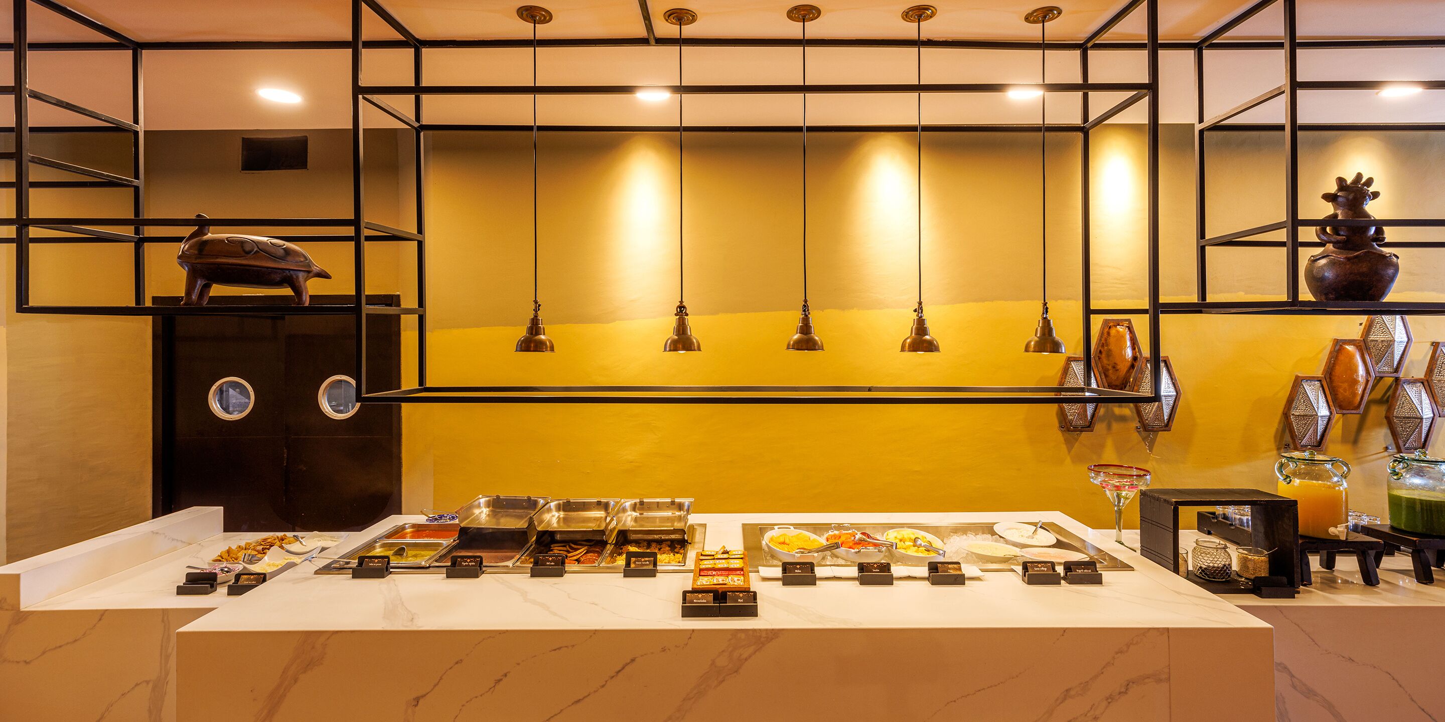A buffet setup with various food and drink options, a decorative turtle sculpture, and a vase on a shelf.