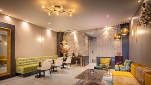 A modern living room with a green sofa, yellow armchair, and a dining area with a table and chairs. - Hotel Oscar (Amsterdam)