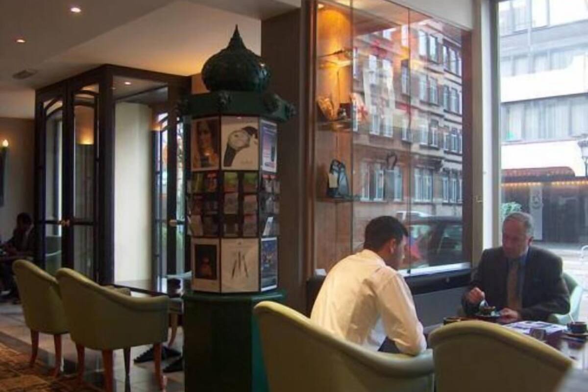 A lobby with a green decorative column, seating area, and a view of the street through a glass wall.