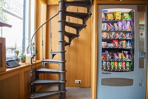 A spiral staircase leading to a window with a view of the street. - Hotel Library Amsterdam (Amsterdam)