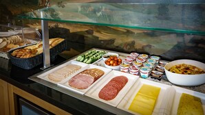 A buffet with various food items including bread, ham, salami, and cheese. - Hotel Library Amsterdam (Amsterdam)