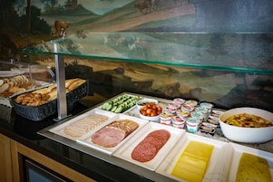 A buffet with various food items including bread, ham, salami, and cheese.