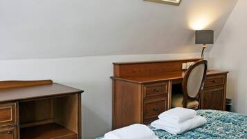 A bedroom with a bed, a wooden dresser, a mirror, and a desk.