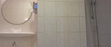 A bathroom with a round mirror, a sink, and a shower.