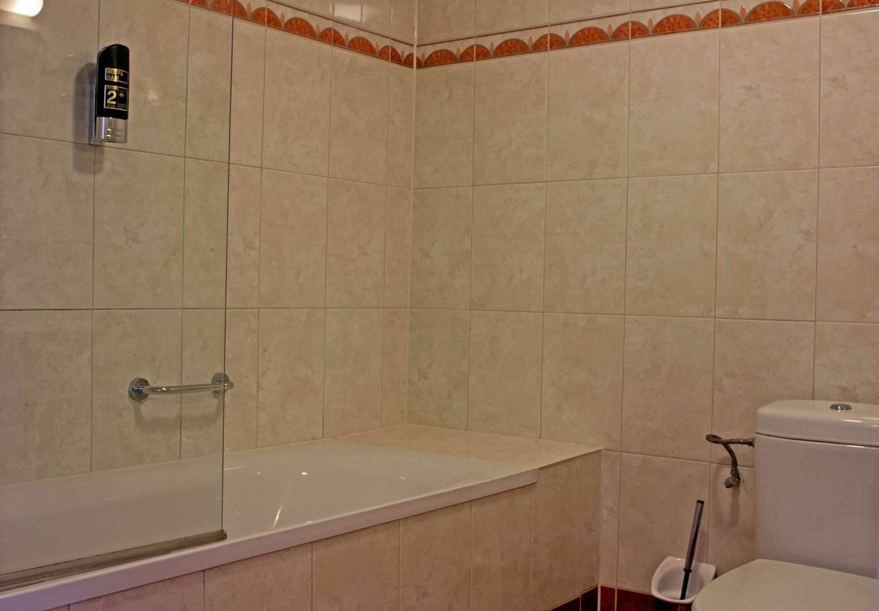 A bathroom with a bathtub, toilet, and a hand dryer.