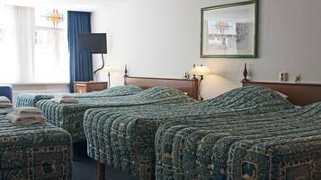 A hotel room with three beds, a television, a framed picture, and a window with curtains.