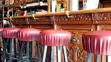A bar area with wooden bar stools and a shelf with bottles.
