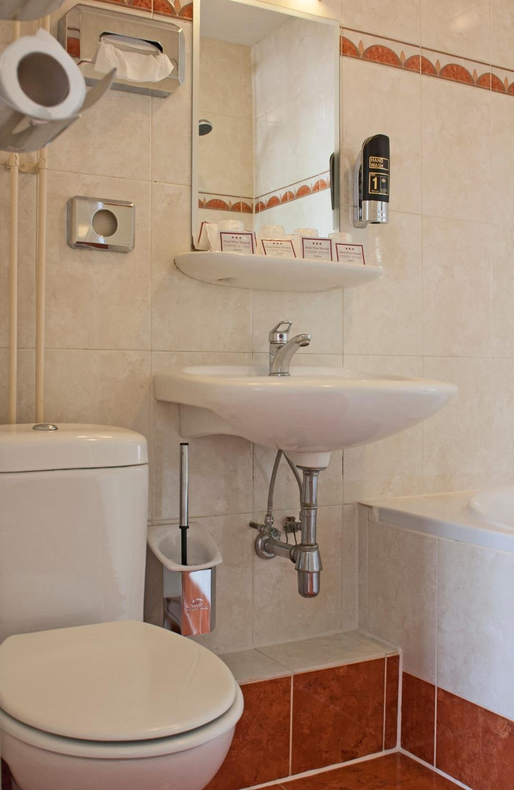 Un baño con inodoro, lavamanos y dispensador de gel antibacterial.