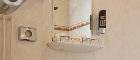 Un baño con inodoro, lavamanos y dispensador de gel antibacterial.