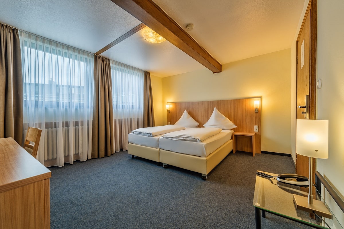 Ein Hotelzimmer mit Bett, Nachttischen, Schreibtisch und Lampe.