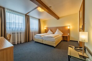 A hotel room with a bed, bedside tables, a desk, and a telephone. - Windsor Hotel (Cologne)