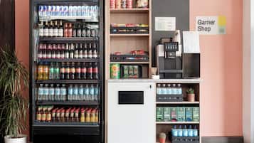 Een automaat met diverse drankjes en snacks, een koffieapparaat en een bordje voor een Garner Shop.