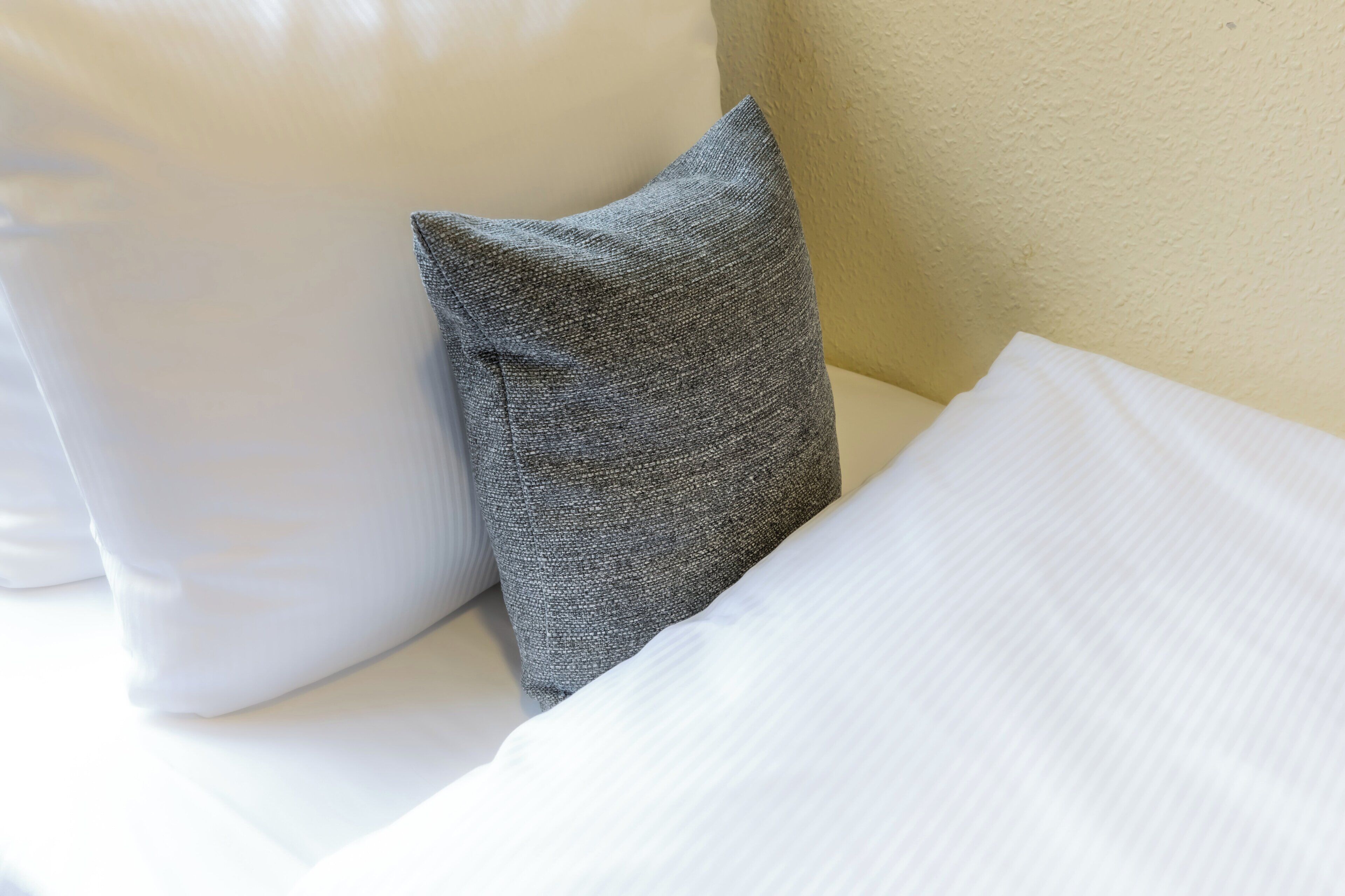 A bed with white and gray pillows.