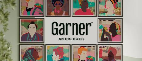 Una colección enmarcadas de arte colorido en una pared, con el texto "Garner AN IHG HOTEL" en el centro.