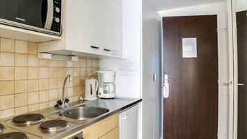A kitchen with a microwave, stove, coffee maker, and a door with a sign.