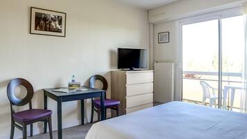 Une chambre d’hôtel avec un lit, un bureau et une chaise, une télévision et une fenêtre donnant sur un paysage agréable.