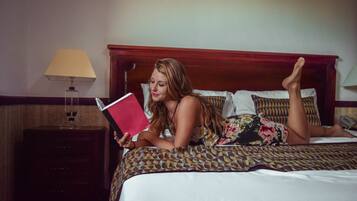 Iemand ligt op een bed met een beddegoed met een patroon, en leest een boek.