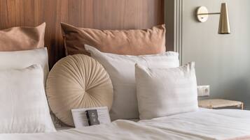 A neatly made bed with multiple pillows and a bedside table with a lamp.