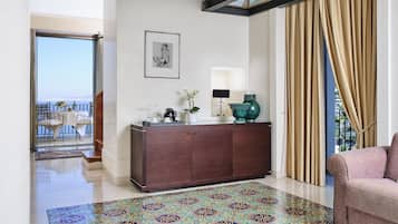Un salon comprenant un grand meuble en bois, un tapis à motifs, un canapé et une vue sur le balcon.