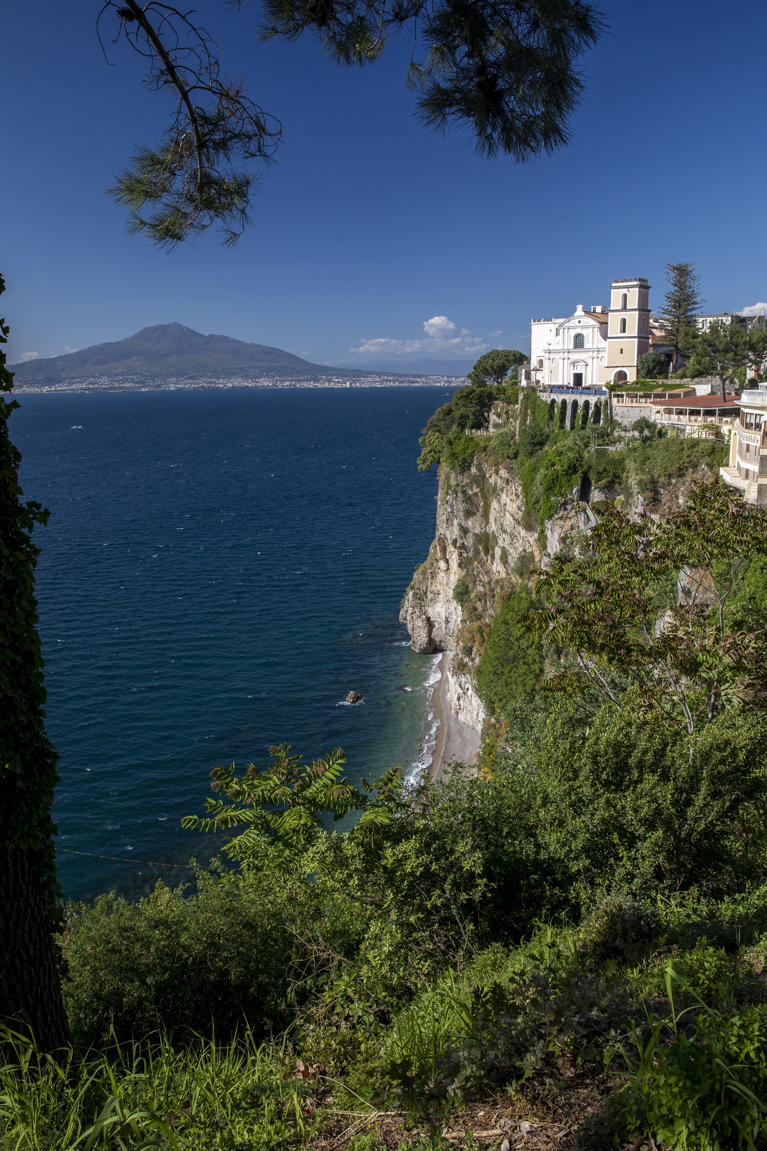 Un bâtiment situé sur la côte, offrant une vue sur la mer et une montagne à l’horizon.