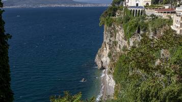 Un bâtiment situé sur la côte, offrant une vue sur la mer et une montagne à l’horizon.