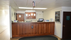 A reception desk with a wooden counter, a no smoking sign, and a sign for vending/ice machines. - Grand Inn Fargo (Fargo)