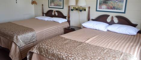 Two single beds with floral-patterned linens, a nightstand with a lamp, and two wall-mounted lamps.